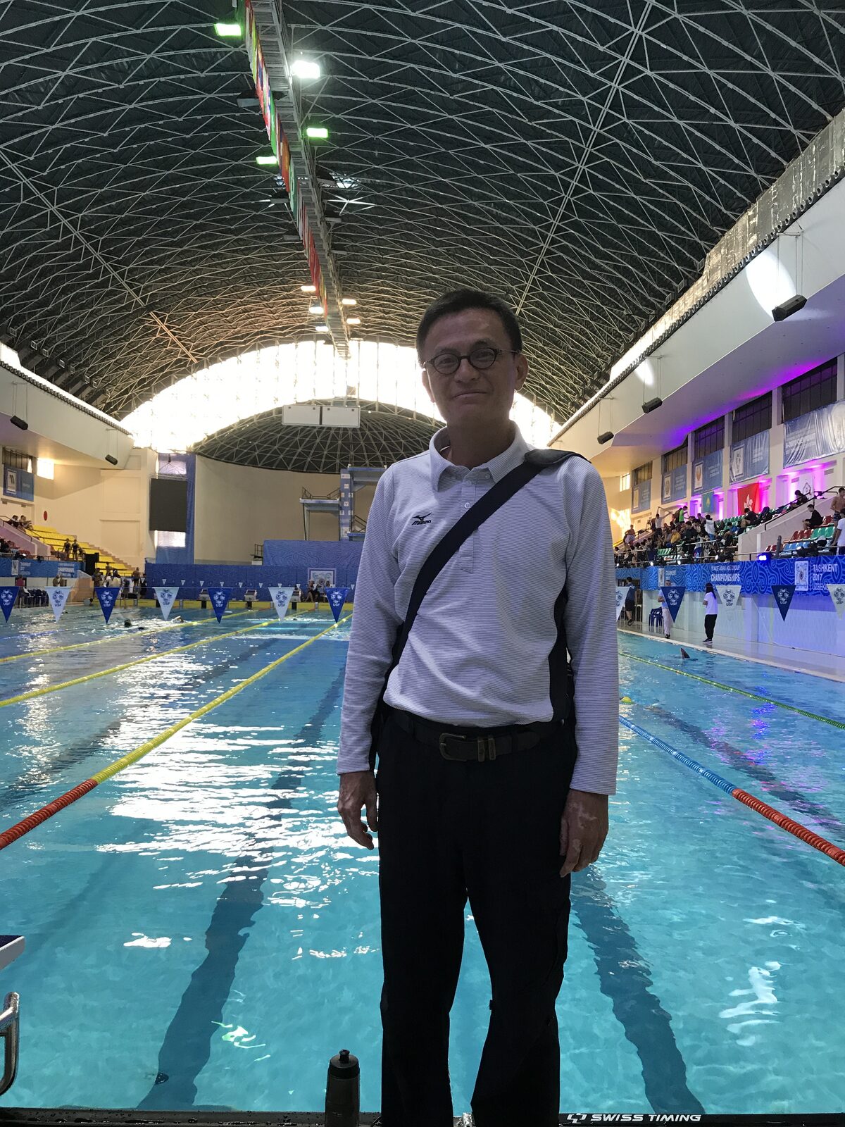 張育銘教練站在比賽場館的泳池畔